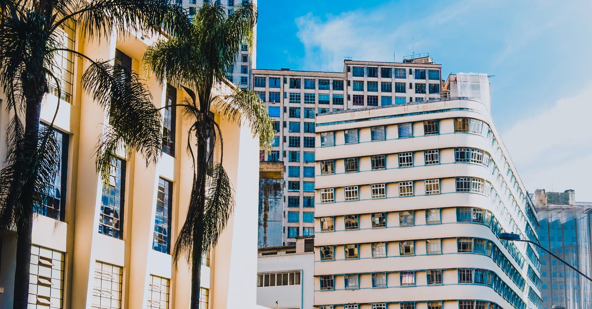A lively urban street with modern buildings under a blue sky, capturing city life.