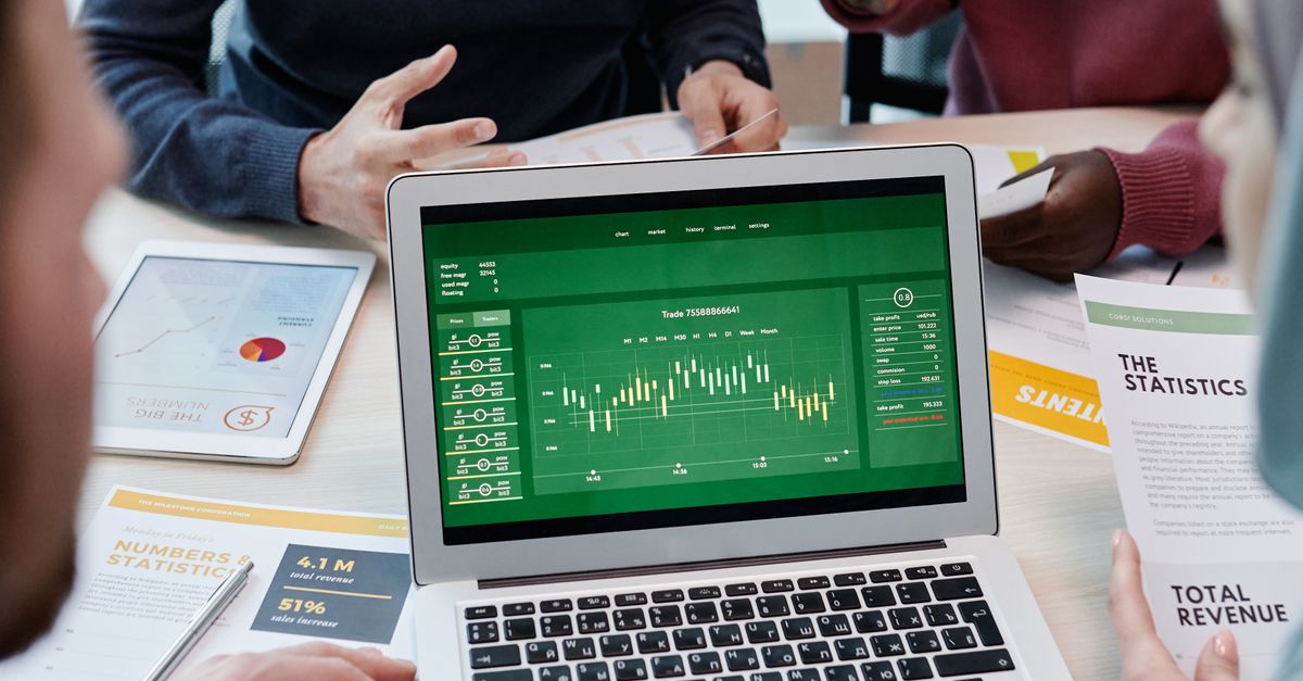 A diverse group of professionals discussing financial charts on a laptop in a modern office setting.