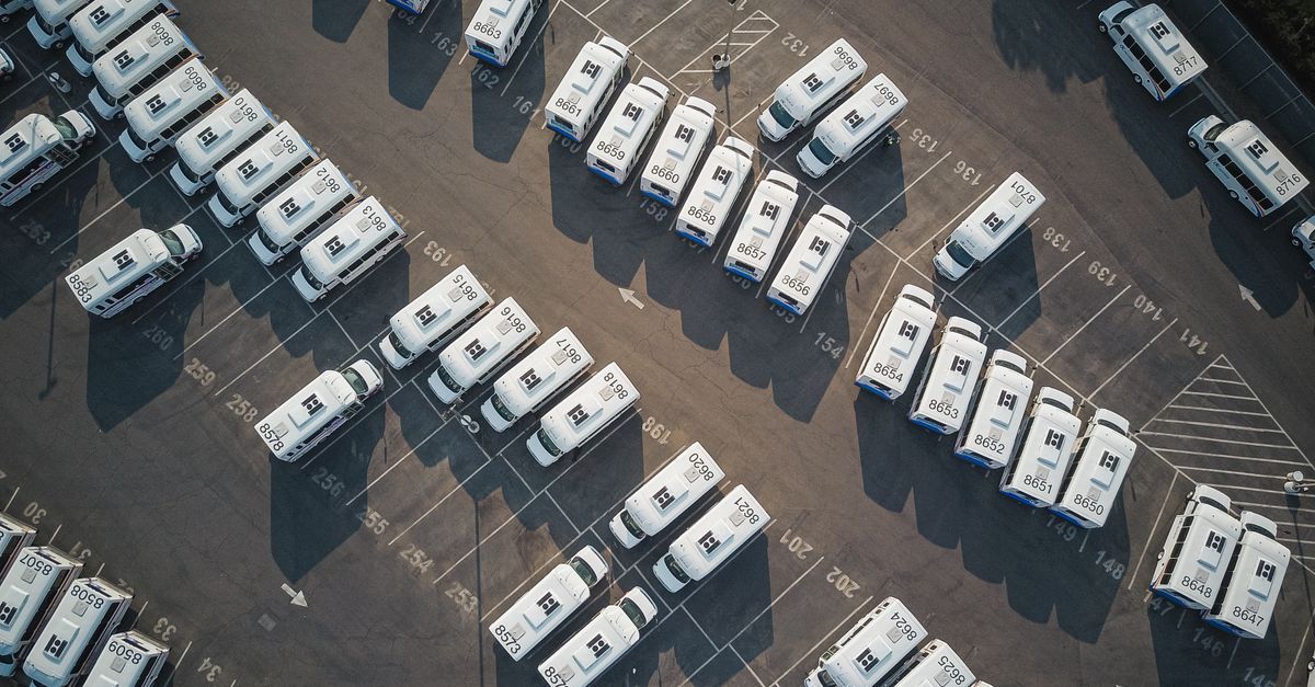 Aerial drone shot of neatly organized vans in a large parking lot.